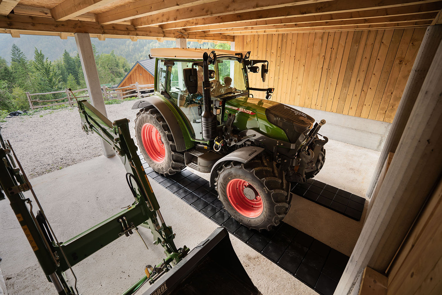 Der Traktor ist in der Garage auf Gehplatten geparkt, die den Betonboden schützen.