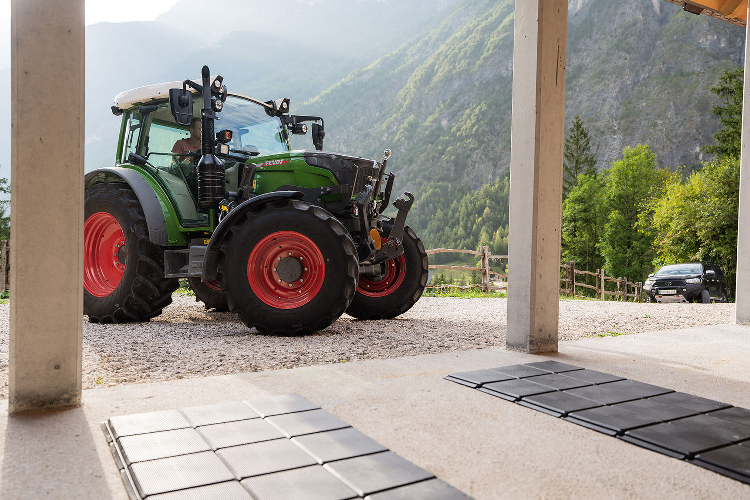 Ein grüner Fendt-Traktor fährt auf den Gehplatten zum Bodenschutz in Richtung Garage