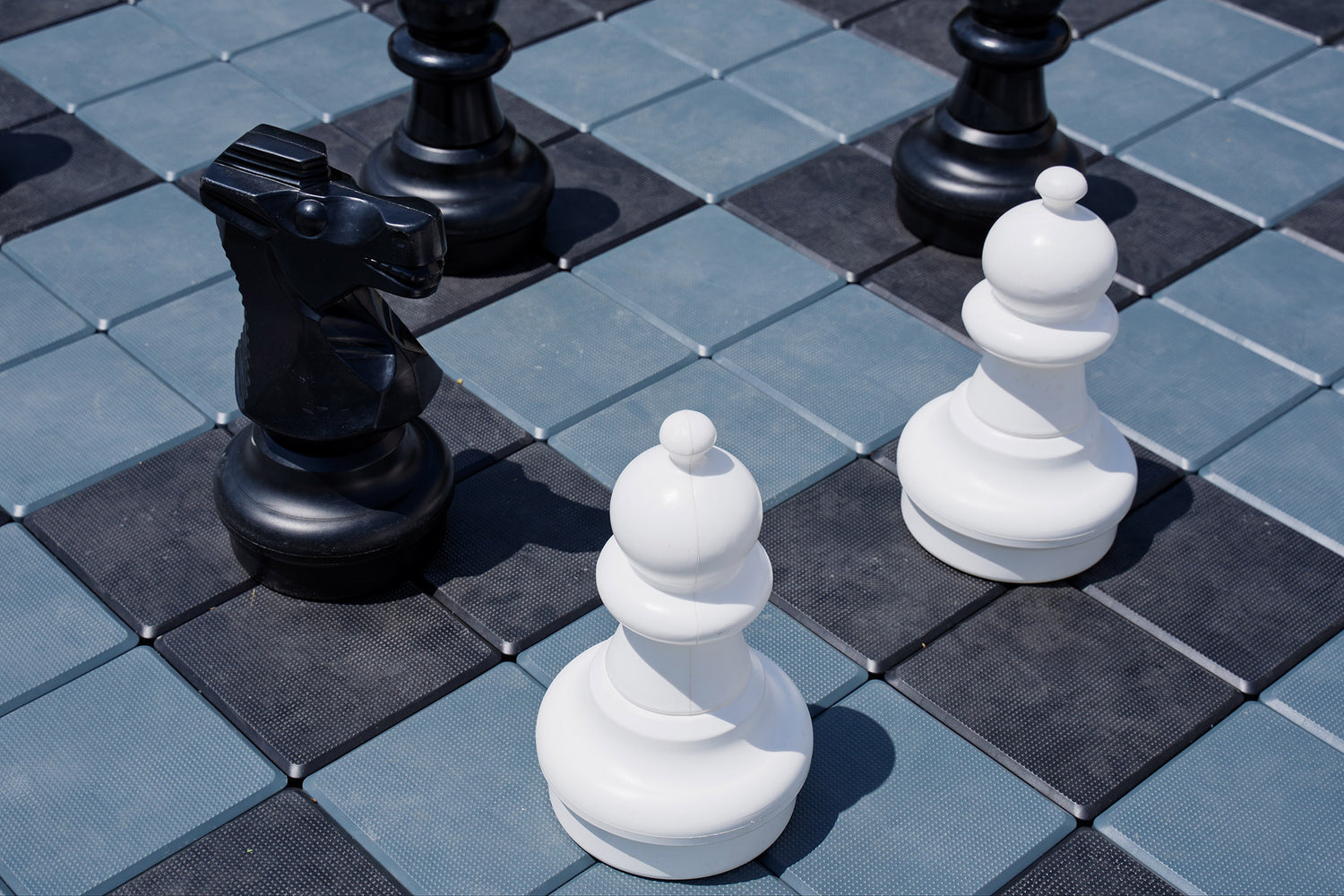 Nahaufnahme von Schachfiguren auf einem Schachbrett, schwarz-weiße Figuren deutlich sichtbar.