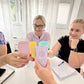 : Gruppe von Menschen stößt im Büro mit farbigen CONTESSA Chakra-Bechern an, fröhliche Atmosphäre während einer Besprechung.