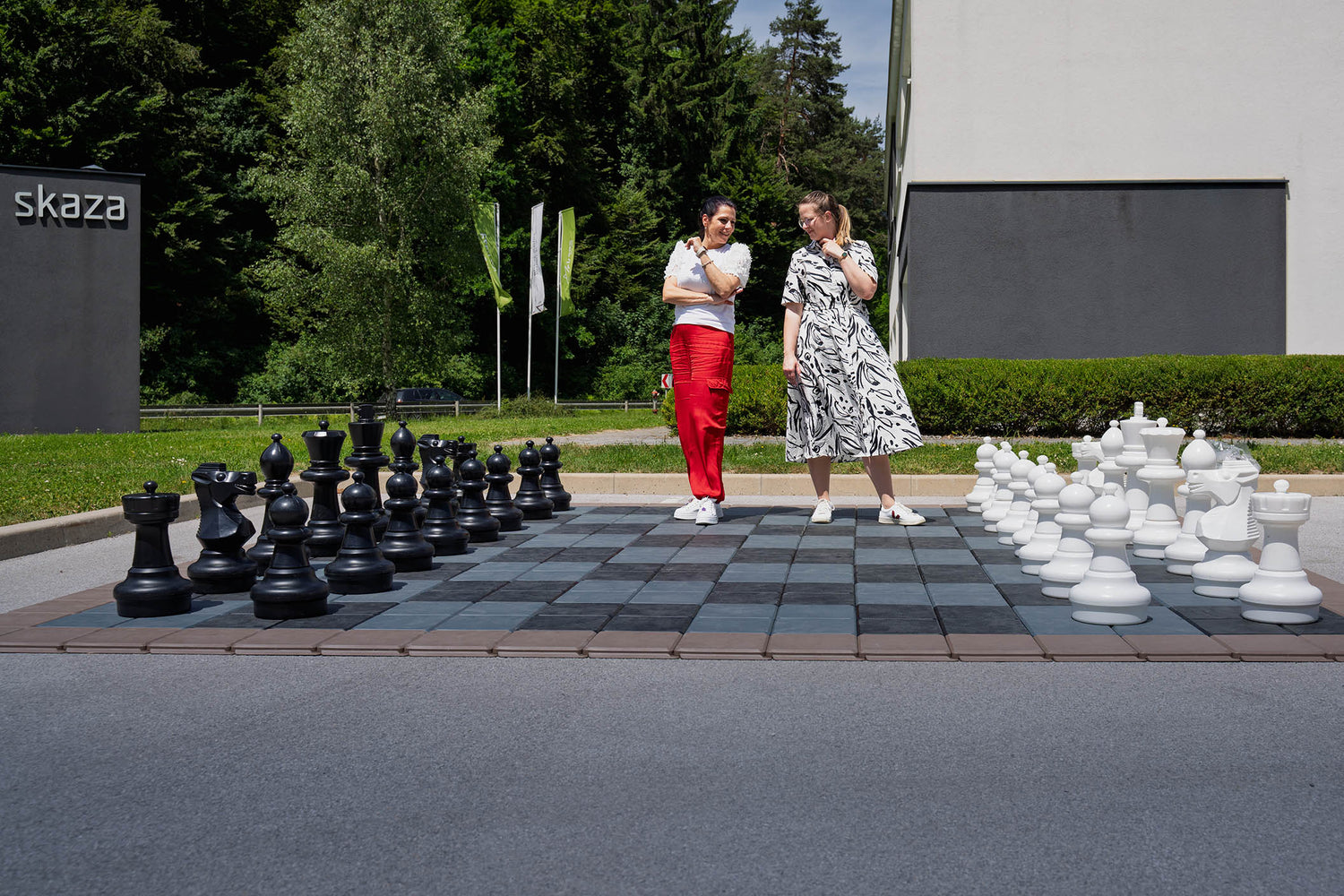 Zwei Frauen spielen auf einem großen Schachfeld Schach.