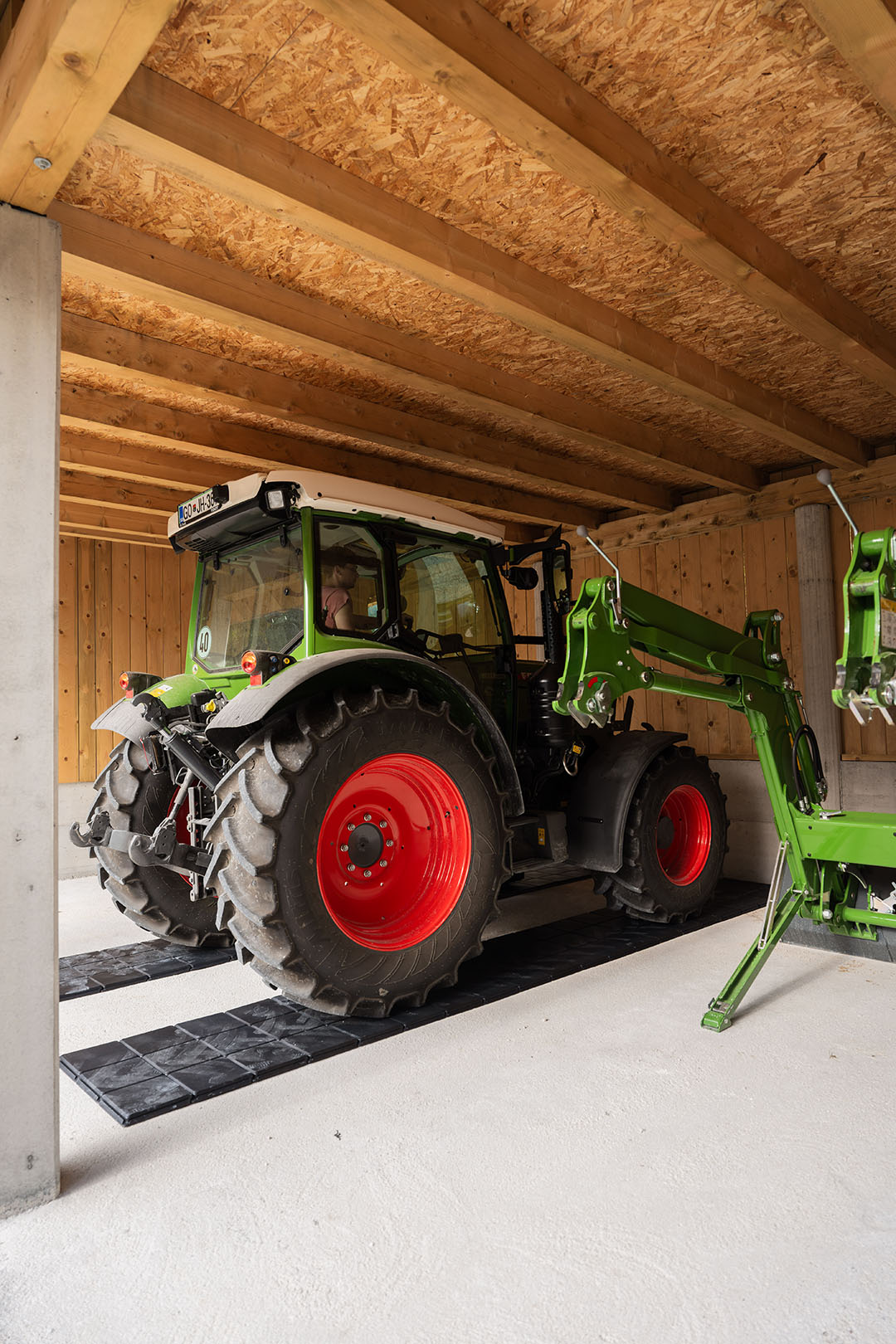 Ein Fendt-Traktor ist in der Garage auf Gehplatten geparkt, die das Gewicht des Fahrzeugs verteilen