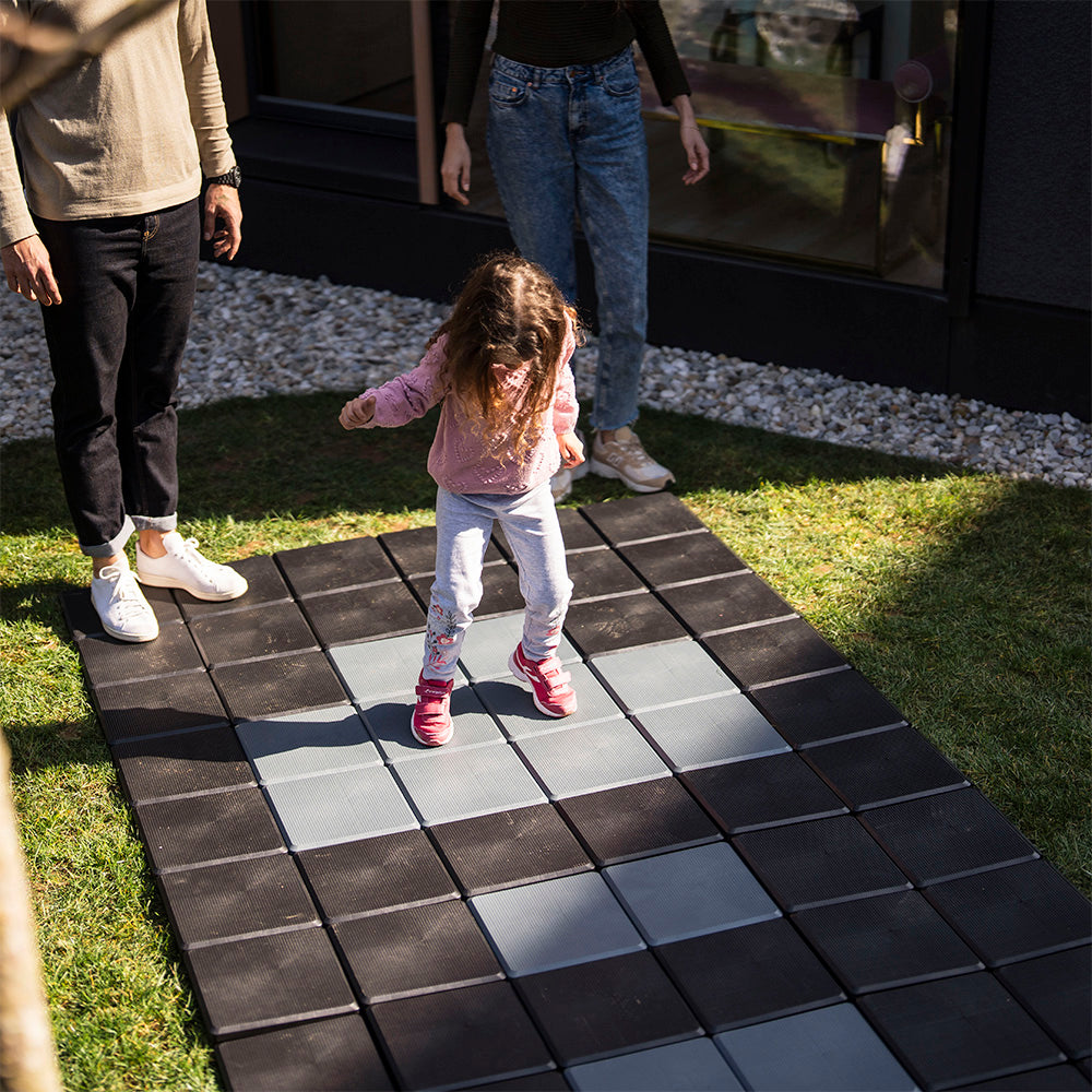 Kind spielt auf Skaza Bodenplatten im Garten – kindersichere, rutschfeste Oberfläche für Familienbereiche im Freien