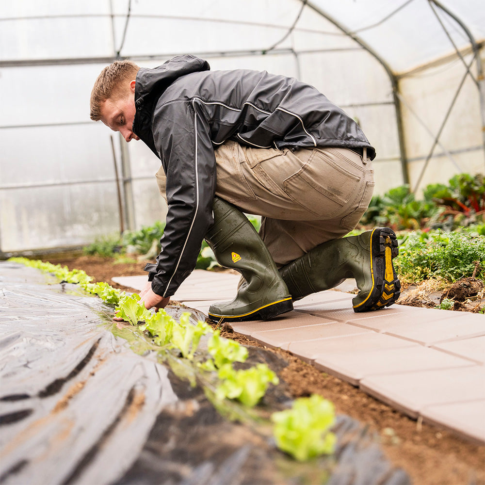 Gärtner arbeitet auf begehbaren Skaza Platten im Gewächshaus – ideal für Gemüseanbau und Gartenwege